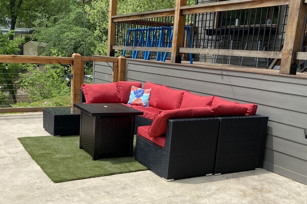A red outdoor sofa with a matching cushion, a small black table, and a green rug on a concrete patio. - Stunning lakefront A-frame home w/ dock! 15% off 4+ nt stay! (Eucha)