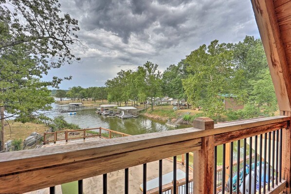 A lakeside view with docked boats, a wooden deck, and surrounding trees.