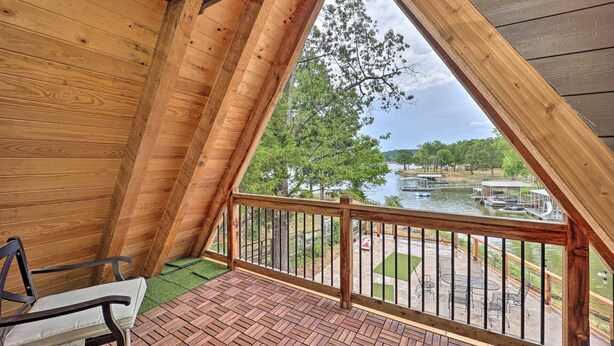 Un balcón de madera con vista a un lago y zona de embarcadero.