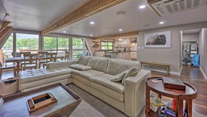 Amplia sala de estar con un sofá seccional beige, una mesa de centro de madera y un comedor con sillas de madera.