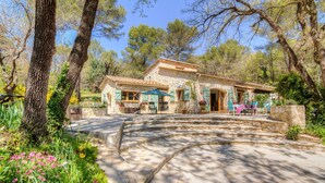 A stone building with a patio, surrounded by trees and flowers. - Charming Estate on 1Ha: 3 Houses, Heated 28 °C Pool, SPA, Ideal for Families (Roquefort les pins)