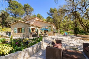 A stone house with a patio, outdoor furniture, and a garden.