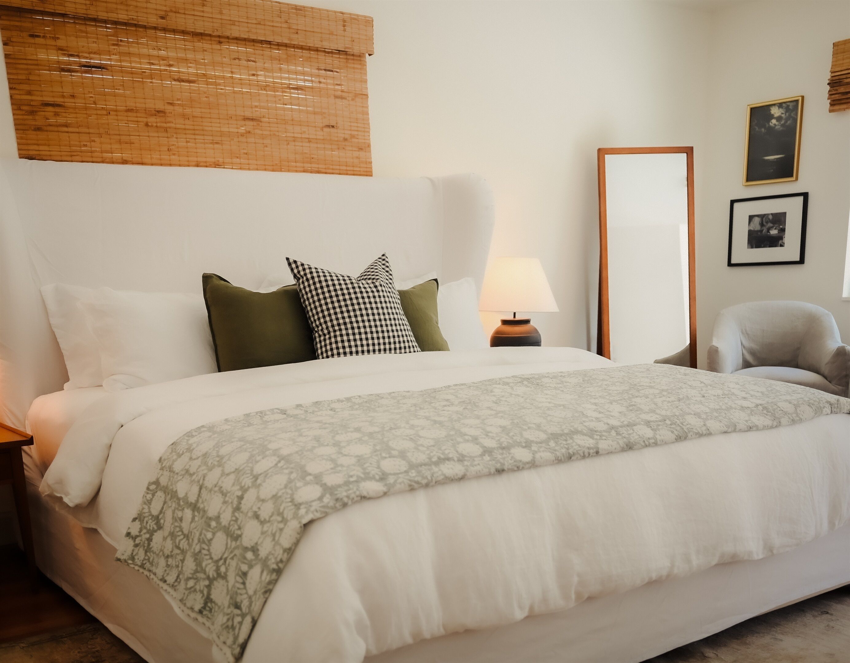 A hotel room with a bed, a nightstand, a lamp, a chair, and a mirror.