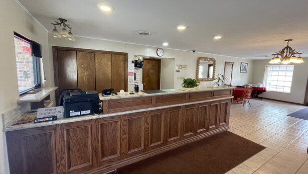 A reception area with a wooden counter, a clock, and a mirror above it. - Village Inn (Ada)