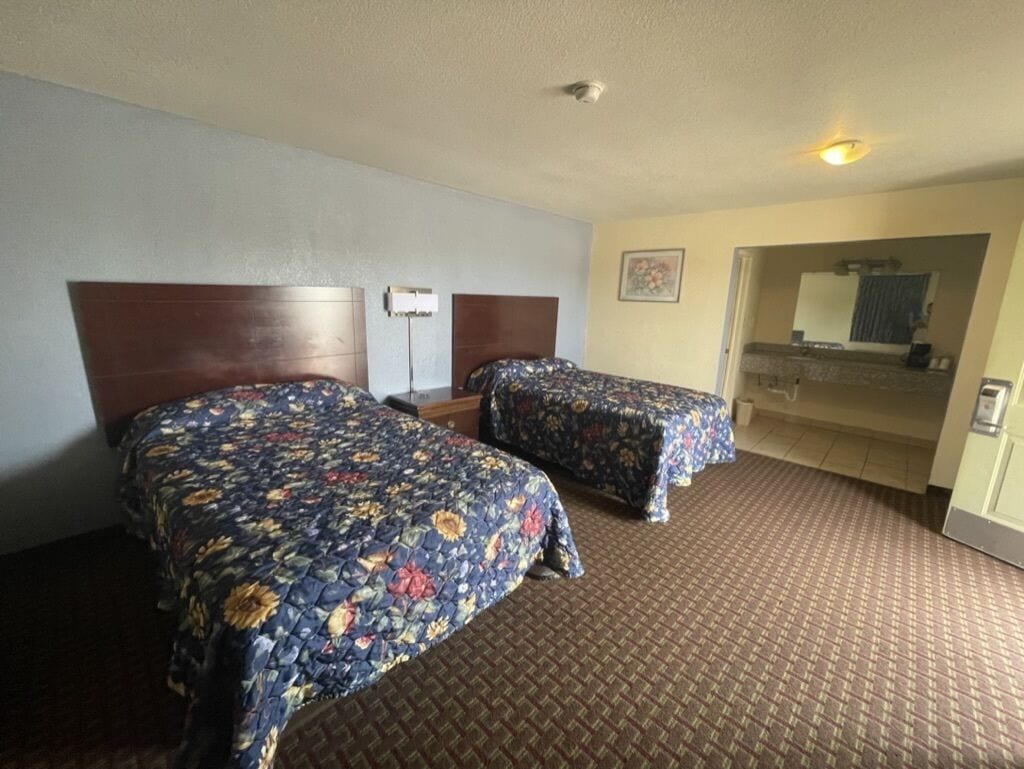 Ett hotellrum med två sängar, ett badrum och en liten sittgrupp.
