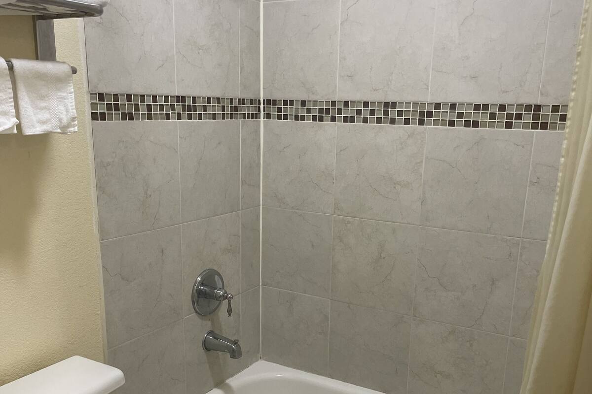 A bathroom with a bathtub, toilet, and a showerhead.