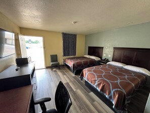 A hotel room with two beds, a desk, a chair, and a window.