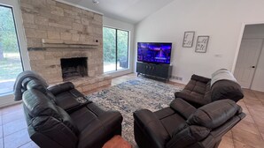 A living room with a stone fireplace, a flat-screen TV, and two leather recliners. - Ranch House (Alba)