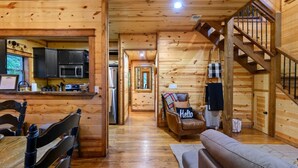 A wooden cabin interior with a kitchen, dining area, and a staircase. - Forward My Calls · Elevate Your Stay: 4 Decks, Hot Tub, & Idyllic Outdoor Haven (Broken Bow)