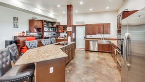 Una cocina moderna con encimeras de granito, electrodomésticos de acero inoxidable y armarios de madera.