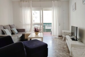 Un salon avec un canapé, une table basse, un téléviseur et un balcon offrant une vue agréable.