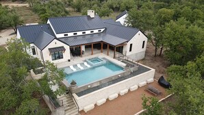 Une grande maison avec une piscine, un patio couvert et une terrasse en pierre.