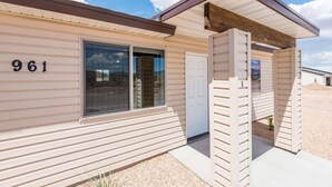 A single-story mobile home with a beige exterior, a large window, and a door. - Brand New Duplex! Minutes from every amenity! (Kingman)