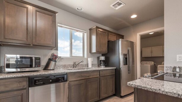 A modern kitchen with stainless steel appliances, granite countertops, and wooden cabinets. - Brand New Duplex! Minutes from every amenity! (Kingman)