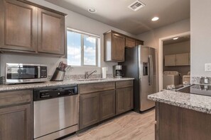 A modern kitchen with stainless steel appliances, granite countertops, and wooden cabinets.