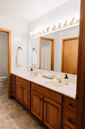 A spacious bathroom with a double sink vanity, mirror, and ample lighting.