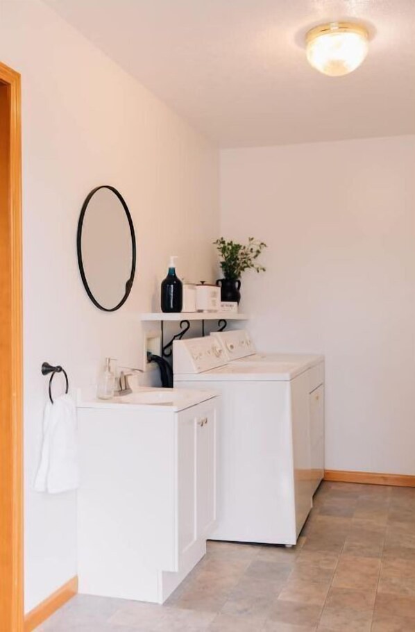 A laundry area with a washing machine, a dryer, and a shelf with toiletries. - Country Cottage (Nappanee)