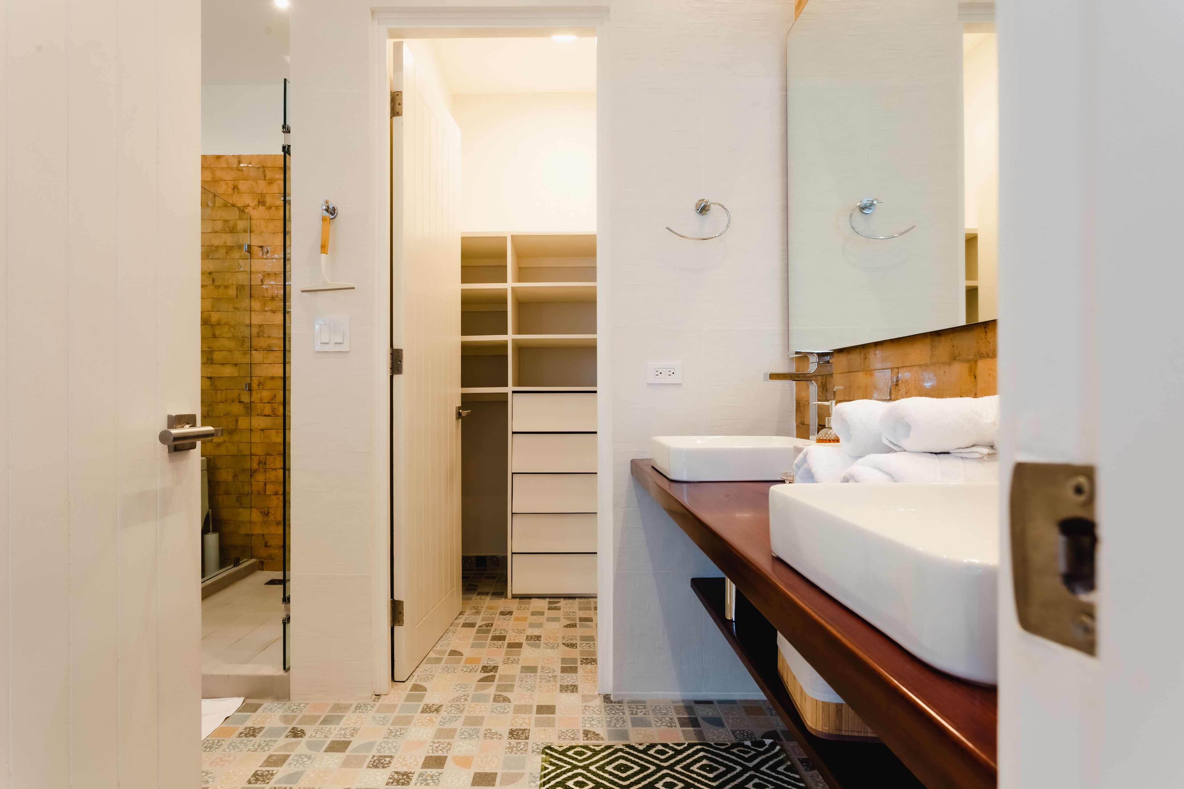 A modern bathroom with a shower, a sink, and a storage cabinet.