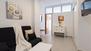 Ein modernes Wohnzimmer mit einer schwarzen Couch, einem weißen Couchtisch und einer weißen Konsole mit einem Blumenstrauß.