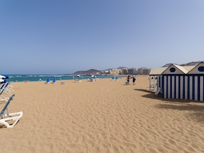A beach with clear skies, blue umbrellas, and beach chairs. - Sweet House Las Canteras (Las Palmas de Gran Canaria)