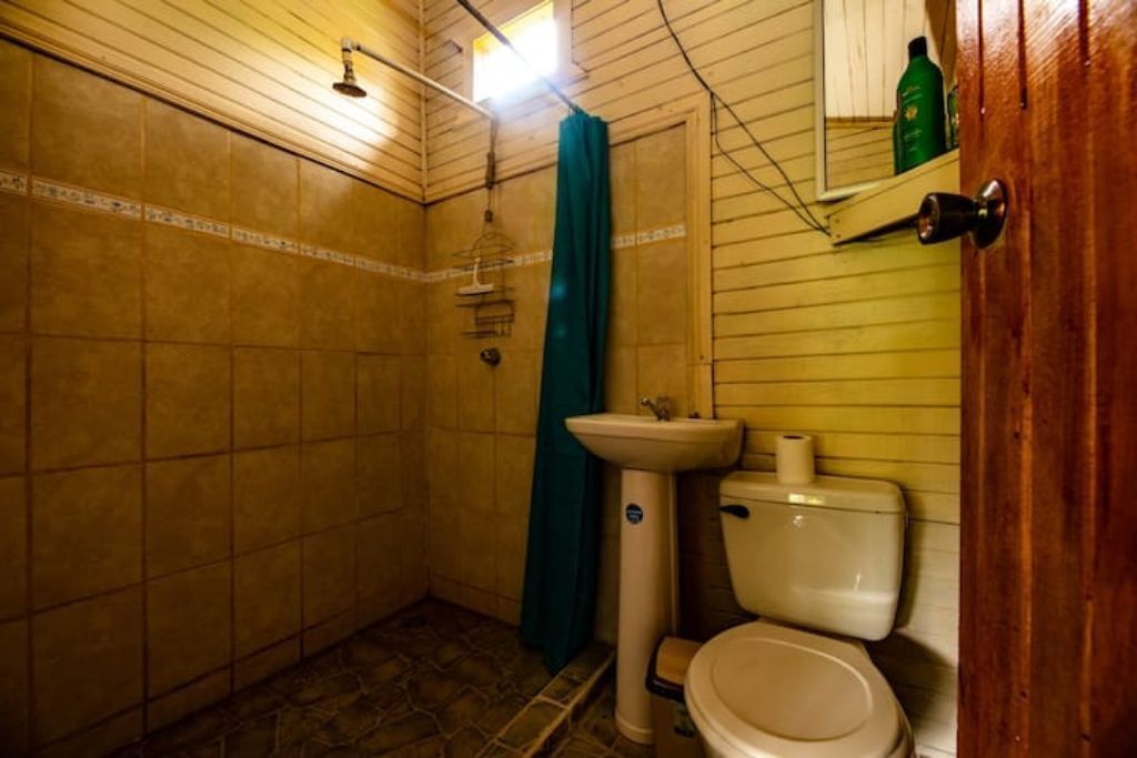 Un baño pequeño con inodoro, lavamanos y ducha.