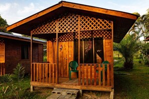Una cabaña de madera con un porche cubierto, una ventana y una puerta.