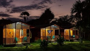 Une rangée de cabanes en bois, dotées de balustrades en treillis, chacune ayant une véranda et une chaise.
