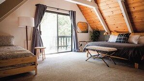 A bedroom with a wooden ceiling, a bed, a bench, a desk, and a large window. - Good Life Cabin- EV-Hot Tub-Lake Access-Pups OK (Arnold)