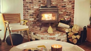 A cozy room with a brick fireplace, a wooden chair, and a table with a candle. - Good Life Cabin- EV-Hot Tub-Lake Access-Pups OK (Arnold)