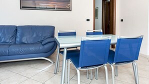 Une pièce avec un canapé bleu, une table en verre et quatre chaises bleues.