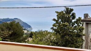 Une vue côtière avec une montagne, des arbres et un bâtiment doté d’un toit en tuiles.