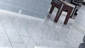 Un salon moderne avec un téléviseur à écran plat fixé au mur, un coin repas avec une table et des chaises, et une cuisine en arrière-plan.