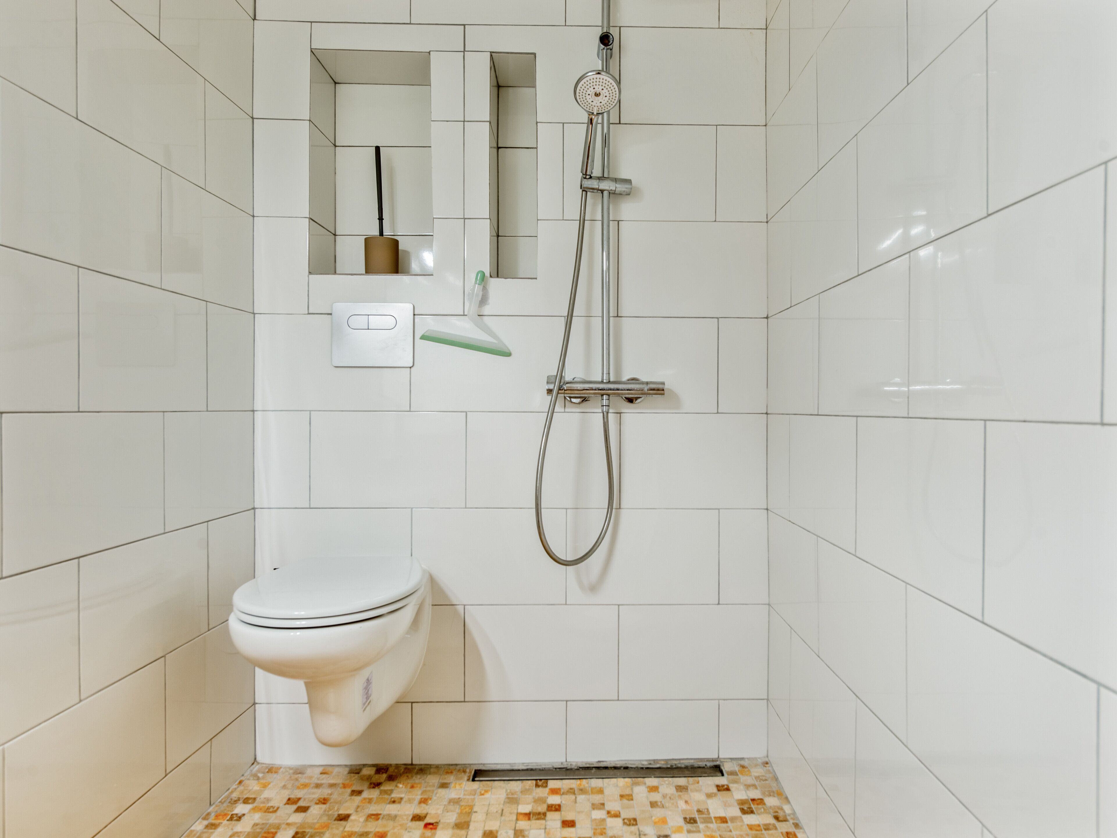 Un baño con inodoro, ducha y espejo.