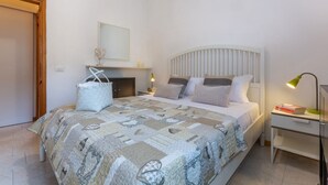 A bedroom with a bed, bedside tables, a nightstand, a mirror, and a door. - Villa with garden on two levels (ground floor and first floor) with internal stairs.In 70 square meters of space, it comfortably accommodates 6 people with two bedrooms (one with a double bedroom, one with two single beds) and a double sofa bed in the li (Lido di Spina)