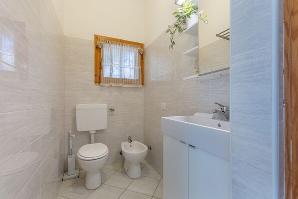 Un baño con inodoro, bidé y lavamanos.