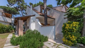 Una casa de dos pisos con fachada blanca, un porche cubierto y un camino de piedra que lleva a la entrada.