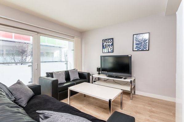 Relax in this stylish living room with a black leather sofa, flat-screen TV, and beautiful views.