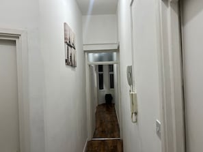 Enter a cozy hallway with a door leading to a room featuring a window and a mounted telephone.