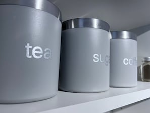 Three cylindrical containers with beverage labels are neatly arranged on a shelf.