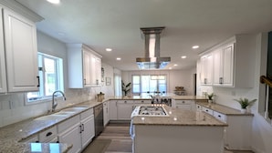 A spacious kitchen with white cabinetry, granite countertops, and a central island. - Peaceful Gathering Place with 12 bedrooms and 7 bathrooms. Game Tables and Pool! (South Bend)