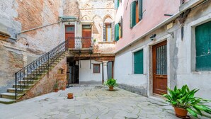 A courtyard with a stone floor, a staircase, and potted plants. - GuestHost - Apartment located on the first floor of an ancient building without a lift.Splendid view of the canal from where the typical Venetian gondolas pass.It accommodates 4 people in 85 square meters of space with two double bedrooms.We are located  (Venezia)
