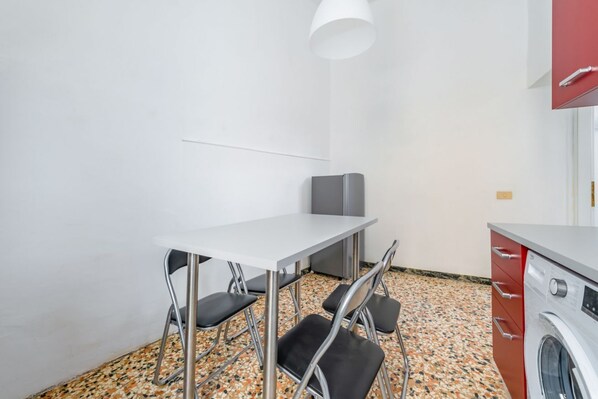 A small kitchen with a washing machine, a table, and chairs.