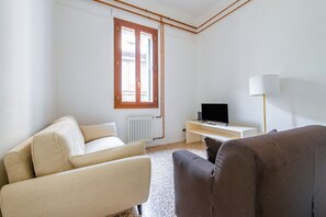A minimalist living room with a sofa, a television, and a lamp.