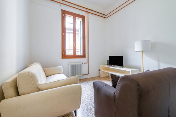 A minimalist living room with a sofa, a television, and a lamp.