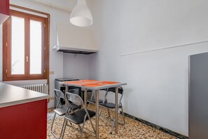 A compact kitchen with a table, chairs, a radiator, and a window.