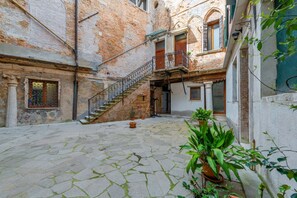 A courtyard with a cobblestone floor, a staircase, and a potted plant.