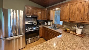 A kitchen with wooden cabinets, stainless steel appliances, granite countertops, and a window. - Seneca Lake View Retreat sits secluded on a 2 acre lot. (Himrod)
