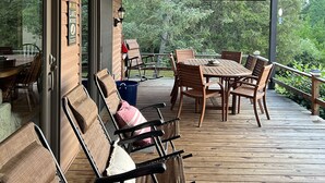 A covered outdoor deck with wooden furniture, including chairs and a table, and a sign indicating a lake house. - Seneca Lake View Retreat sits secluded on a 2 acre lot. (Himrod)