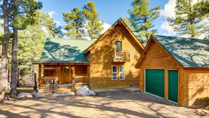 A wooden cabin with a front porch, a balcony, and a garage. - Rustic Pagosa Springs Cabin w/ Hot Tub + Game Room (Pagosa Springs)