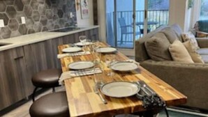 Een eetgedeelte met een houten tafel voor vier personen, een stenen achterwand en uitzicht op de omgeving.